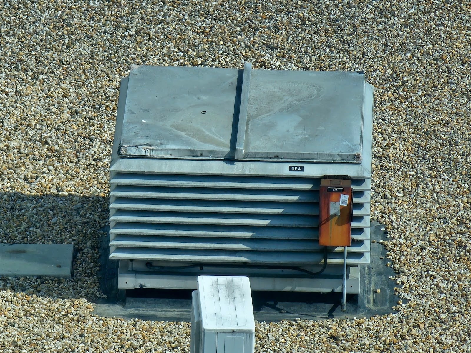 Ballasted flat roof system with stone aggregate covering waterproof membrane