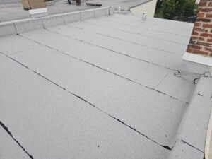 One conversation that comes up with us and our clients all the time is whether or not they should repair their existing roof or get a new roof. The difference is really sometimes the existing old roof is in such bad condition that it's not worth trying to patch it up more. Instead of continuing to kick the can down the road, sometimes it's just better to put a new roof on the building. Today we're going to look at a couple examples of things that are beyond the point of just repair. In the picture below, you can see a new modified bitumen granulated style membrane. We generally recommend the use of TPO membranes with a metal coping instead of the slightly older style of modified bitumen. There's some advantages to new TPO roofs. A new TPO roof can create significant energy savings for a building. People sometimes refer to this as energy efficiency, but a TPO roof reduces heat load gain significantly in the hottest summer months. It can literally reduce cooling cost drastically in the summer. TPO roofs are most commonly a bright white color. In contrast, the modified bitumen roof in the picture below, is a medium grey color. That subtle differences can be significant in terms of solar reflectivity. Here though, today, we are looking at this new modified bitumen roof as a counterpoint to the older roofs we will look at in this article and series. The picture below shows an older modified bitumen roof with a black granule instead of a light gray color granule. At a glance this roof might look similar to the new roof. It is actually in very poor condition though. Regretfully, the client had a solar company install solar panels on top of the roof and cause even more damage. First, it would have been good to install a new roof first. Obviously it's easier to install the roof before the panel system and the panel support system is installed. If you install the new roof at that point before the panel structure and framework is installed you have free access to move and work across the roof surface. After the solar panel.system is installed, it's much more difficult to remove an old roof and install a new one.. You can no longer access the roof surface freely, instead you have to crawl around and under a bunch of different frames just to get to the roof itself. Once the panel system is installed it's no longer conducive to upkeep, maintenance. It is definitely not conducive to repairs or replacement. The second reason It's better repair or replace an old and worn roof before installing solar panels is because the new panels are intended to be in place for many years. Once you put them on, the idea of taking them back off just to do routine maintenance or to remove the roof system is counterproductive. It would be extra work which is costly for no additional benefit. If you are unclear about why this particular roof may be excessively worn and damaged, we can point out a few details without even zooming-in. This particular current roof, at the time of taking a picture, had been on the building for a while already, but was never really properly installed, even way back in the beginning. Back when they installed it, they didn't install it correctly because they didn't properly torch the underside of the modbit membrane. There are actually several defects that are observable or visually apparent right from the surface. There's undulation in the surface of the roof membrane which indicates improper adhesion at the time of the initial install. Seams have also been reworked which indicates delamination has occurred which was caused from improper torching. Just by quickly looking at his roof from a distance, you can see that the seams have been reworked or overlaid or embedded in the interstitial space with an asphaltic mastic after the time of the initial installation. This means that the delamination was discovered and/or concerns for leakage occurred and then this improper type of rework was applied. Both iterations of installation or rework were done incorrectly and the problems have still never been repaired. Here at this point these compiling conditions have led to more problems. As well, the incorrect treatments have increased the difficulty to repair it properly now that the interstitial overlap has been improperly treated with asphaltic mastics. Asphaltic mastics work well in an emergency. For example when there's pouring rain and something needs to be done to stop the inflow of water through a roof system, an asphaltic mastic might be the best choice. Modified bitumen, though, is much better repair using synthetic or polymer materials that have much higher performance than asphaltic materials. Asphaltic materials naturally lack inherent resistance to ultraviolet rays and will not last very long without being recovered themselves. Instead of doing effective repairs on top of the roof that was installed improperly from the first day, and instead of installing solar panels on top of the roof system that's already in bad shape, we highly recommend a replacement and removal of the old roof first. It makes a lot more sense to improve the bad roof condition before moving on to something that is intended to economically lock in a bad substrate. Instead of compiling problems, talk to a professional roof company, install a new roof system and save much more in the long term. Repeated unnecessary iterations of rework is highly counterproductive, both in energy, personal patience and also economic efficiency. In this coming week, we'll take a look at how solar panels, when installed improperly, can cause significant damage to an otherwise good roof system. We provide this information here on our blog, and our website, to help our customers and future clients, and we recommend every building owner in DC who values the longevity of their roof (and their investments) and building use a contractor who values the simple and important principles of proper roof construction like Dupont Roofing DC. Our company specializes in flat roofing here in Washington DC and we're happy to help building owners of almost all types. Learn more about our company and the proper techniques of working with roofing on historic buildings in Washington DC here on our blog at DupontRoofingDC.com, and you can call us at (202) 840-8698 and email us at dupontroofingdc@gmail.com. We are happy to help and at least talk through options.