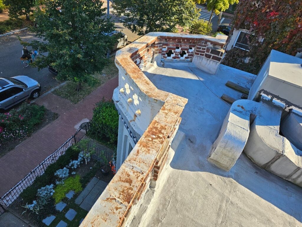Damaged metal flashing separating from brick masonry at a roof edge