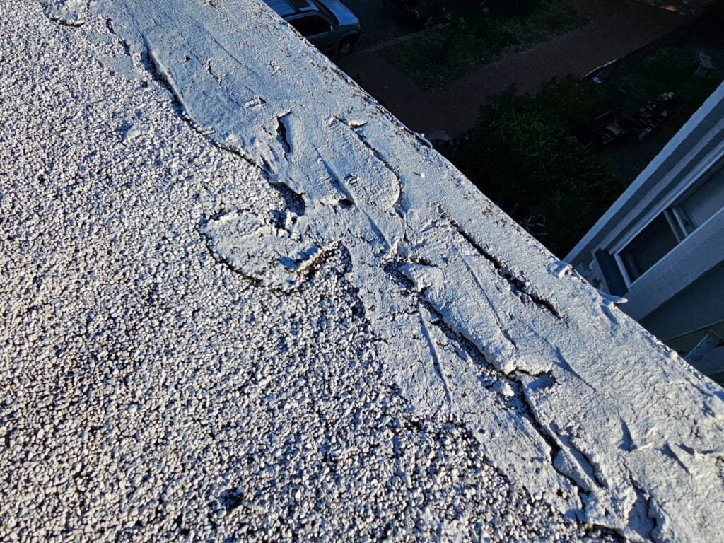 Deteriorated stone coping with cracks and spalling along a historic masonry wall