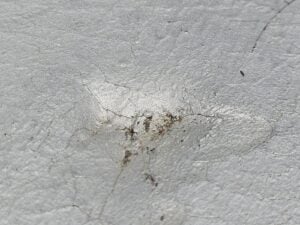 Home 19 Close-up of HVAC impact divot with radiating cracks on modbit membrane, Washington DC