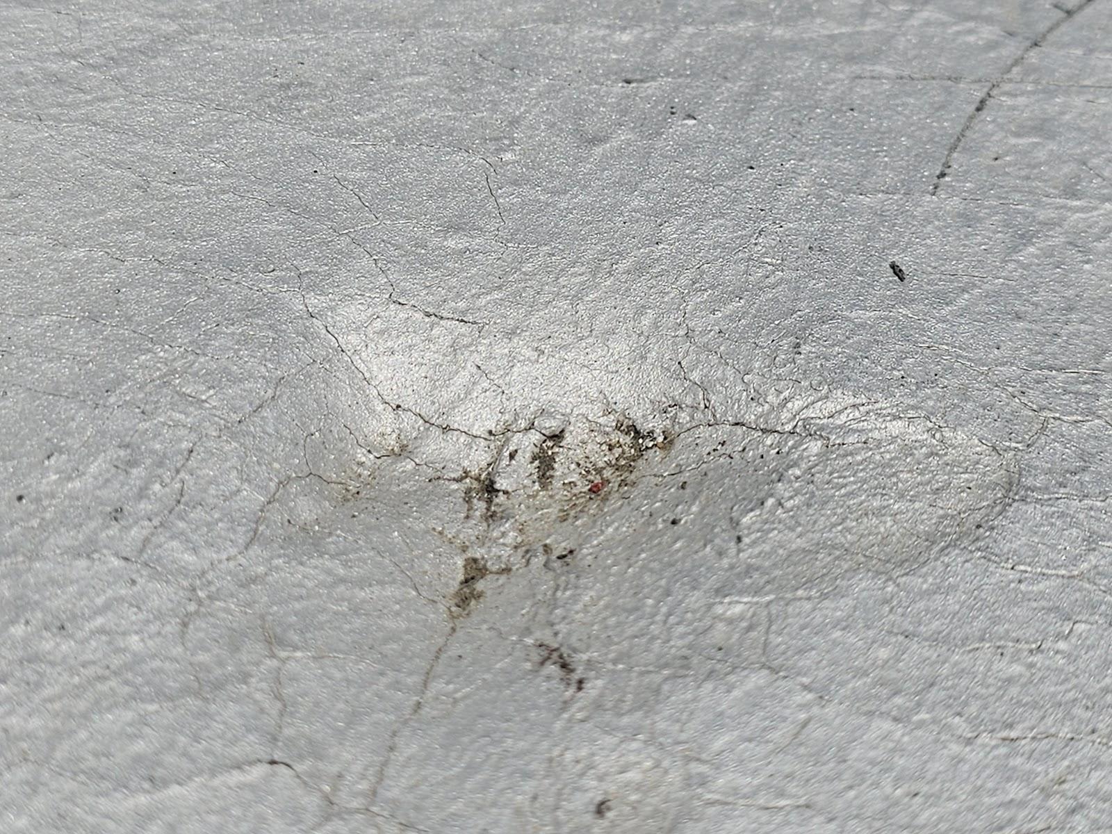 Close-up of HVAC impact divot with radiating cracks on modbit membrane, Washington DC