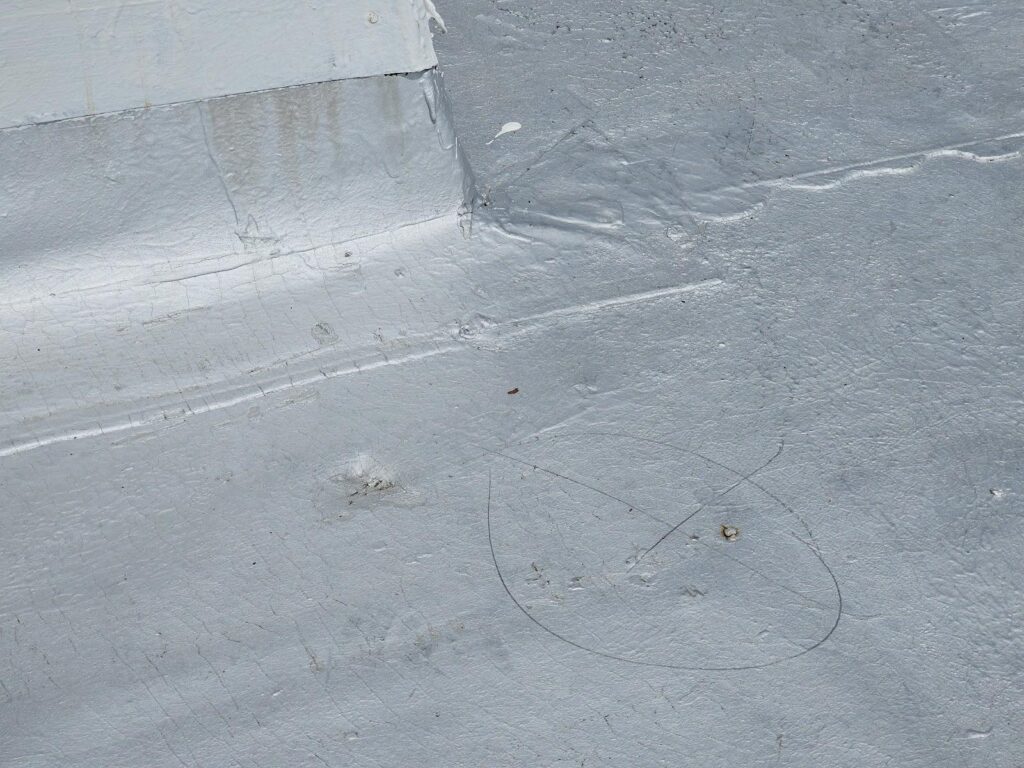 Modbit roof with aluminum coating showing impact divot and nail pop, Washington DC